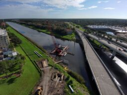 An aerial view of a barge driving piling for the Lake Tarpon Outfall Canal trail bridge.