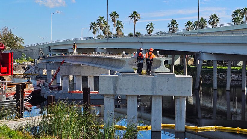 A photograph of workers installing large concrete beams for the Pinellas Trail bridge over the Tarpon Outfall Canal.