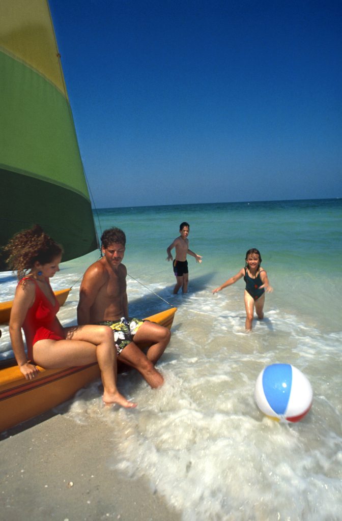 Fort De Soto beach with family playing by sailboat in gulf