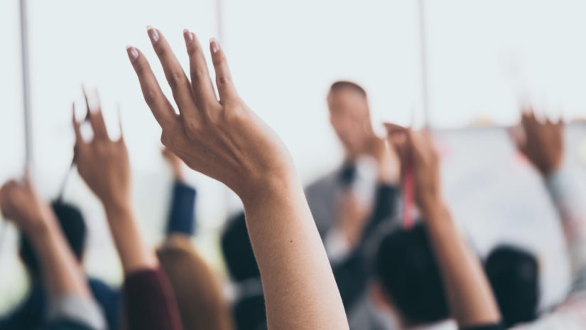 Audience raising hands up wanting to ask question