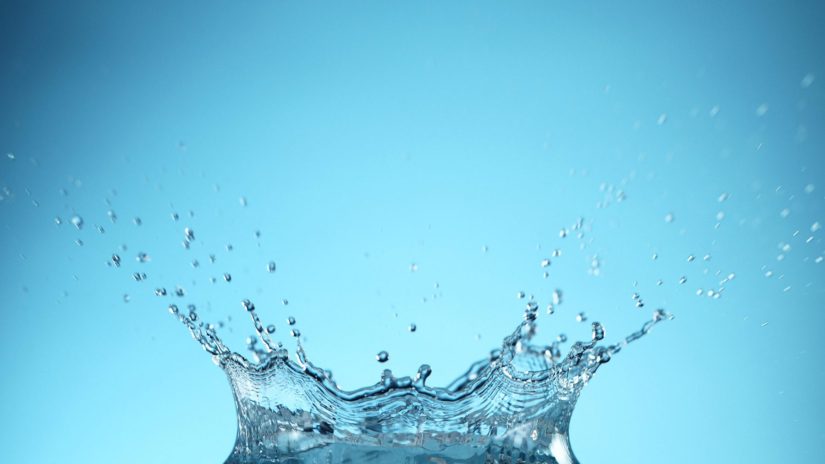 Water splash crown shape on blue background. Free space for text