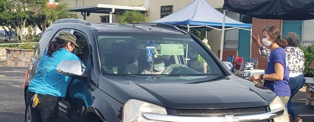 Photo of people giving a driver a kit with hurricane supplies and hygiene items.
