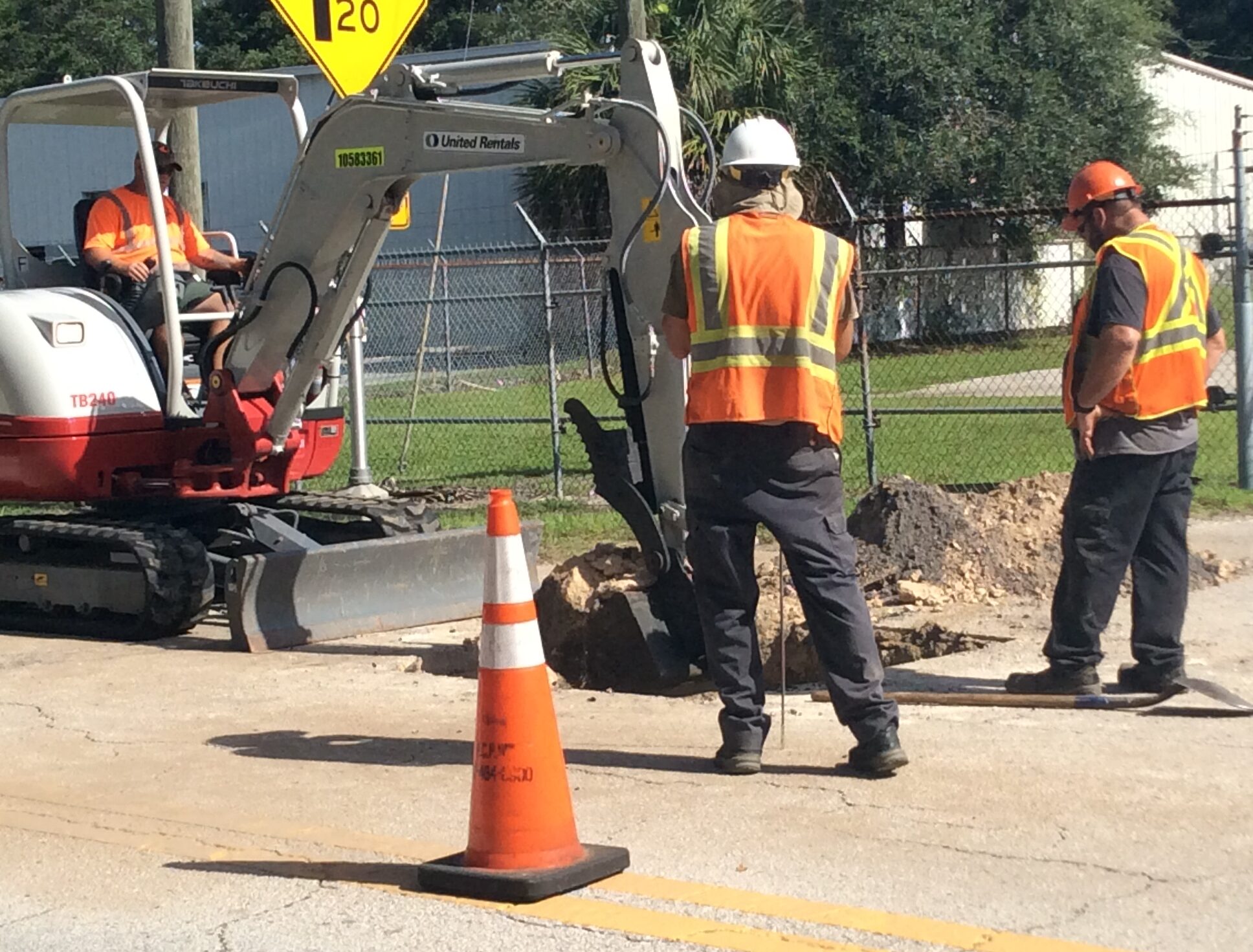 Photo of workers using a small excavator to repair a street