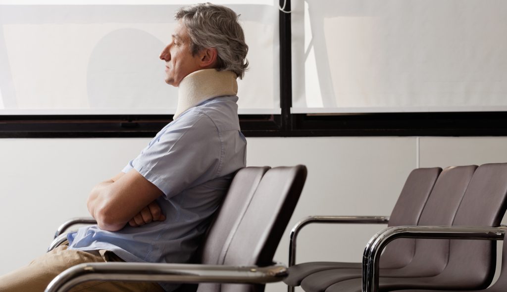 Mature man with neck brace waiting in hospital lobby