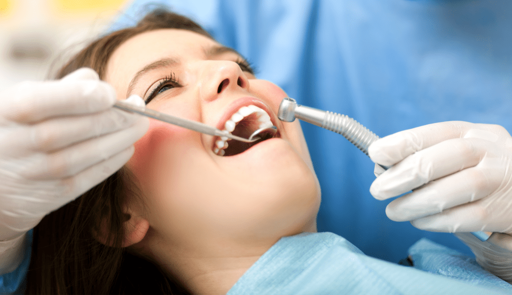 Dental patient in the chair while dentist examines her teeth 