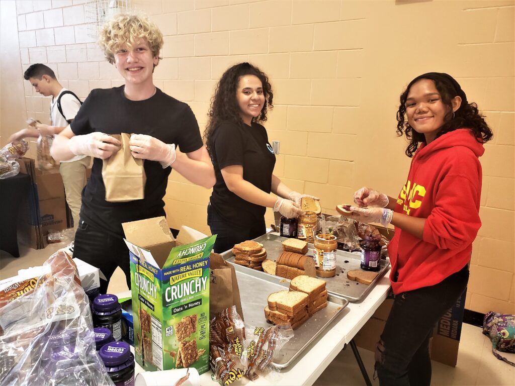 Photo of three teenagers making sandwiches