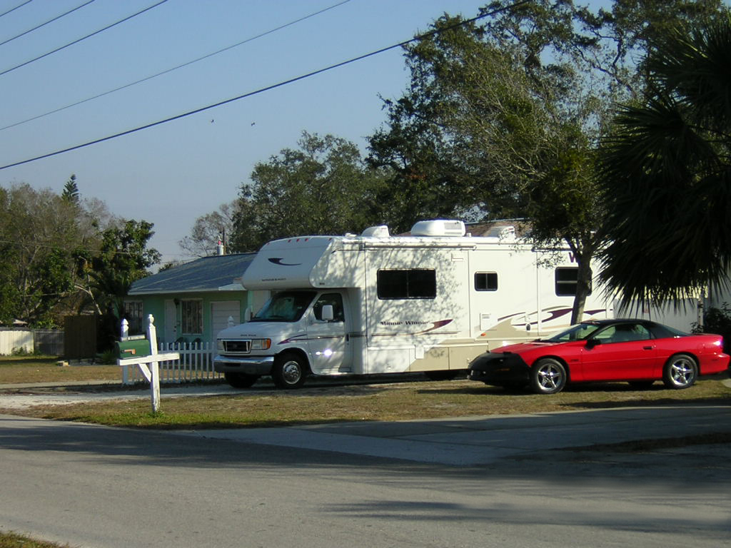 camper parked in driveway and car parked in front yard
