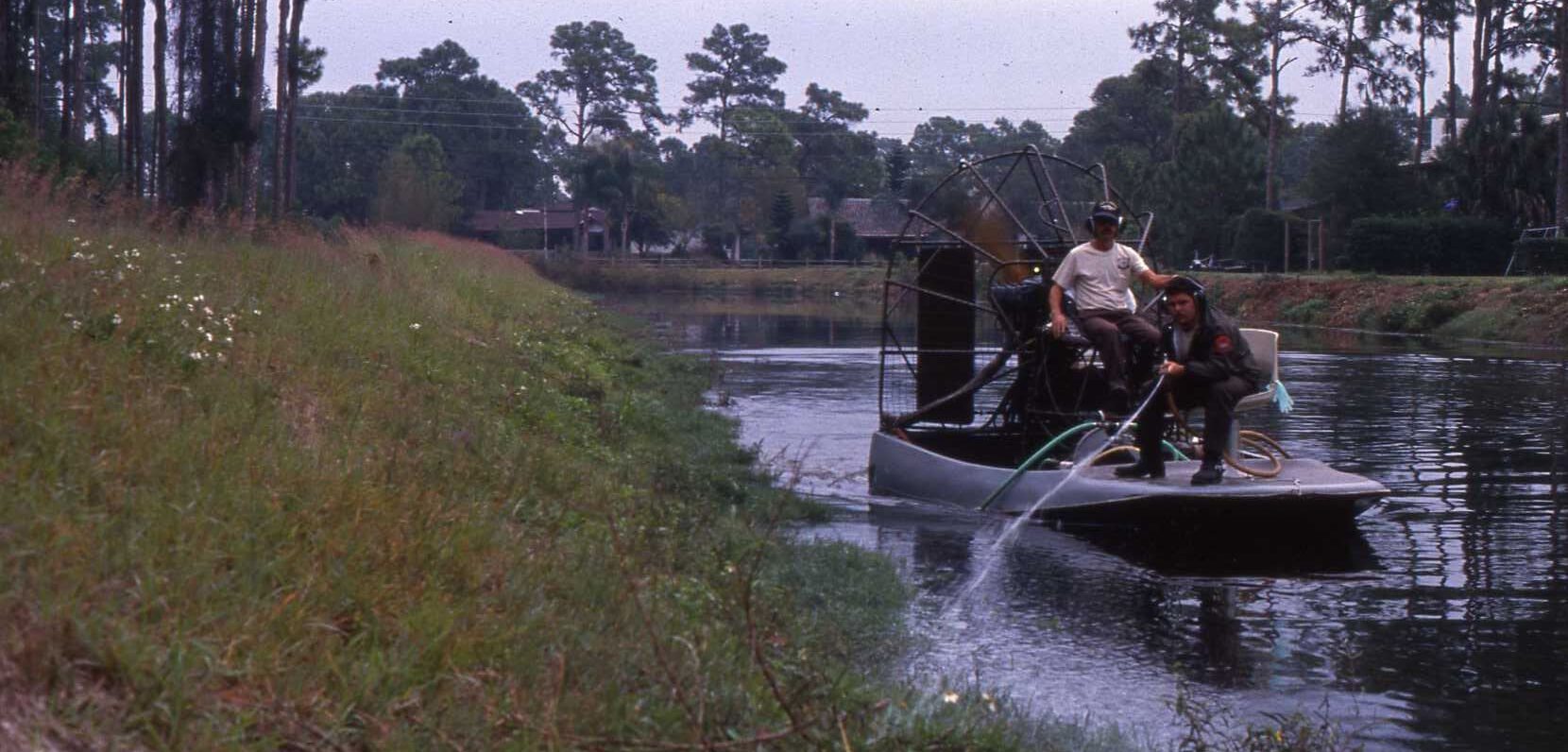 County employees on boat clean up vegetation in water