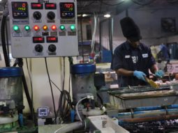 a man wearing gloves works on electroplating equipment