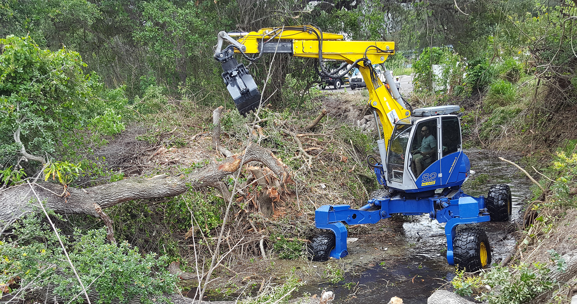 Spider excavator clearing tree debris from stormwater area