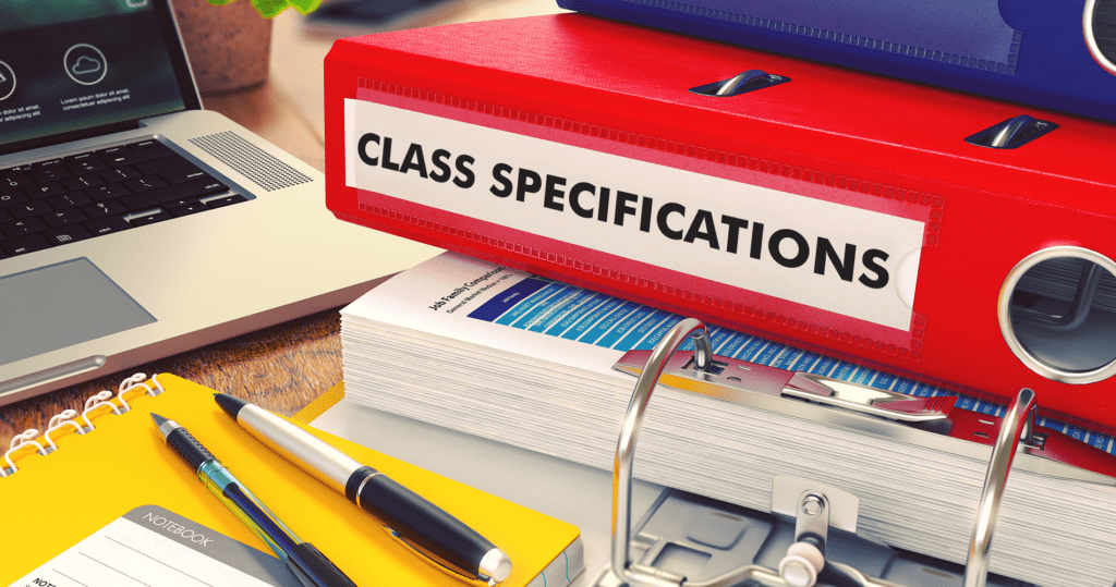 Class specifications binder on a desk with a laptop and pens