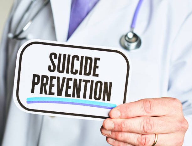 Unidentifiable male in a lab coat holding a medical sign: Suicide Prevention