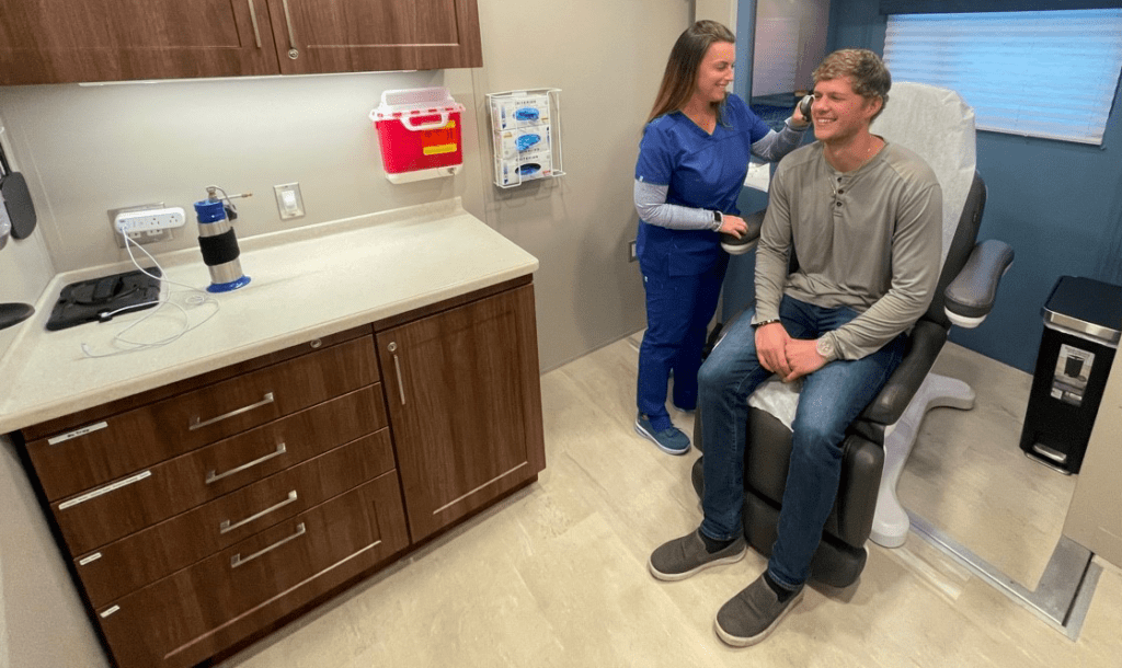 OnSpot mobile dermatology bus interior view with a technician examining a patient