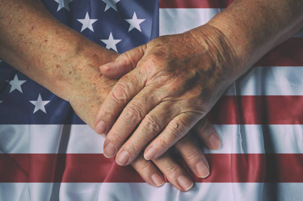 Old woman's hands with American flag, top view.