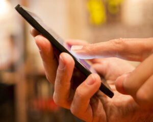 Male hand holding a cell phone in a cafe