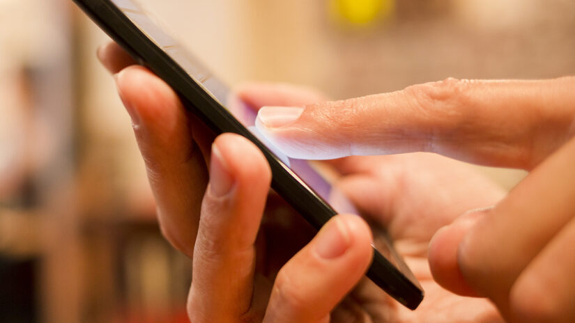 Male hand holding a cell phone in a cafe