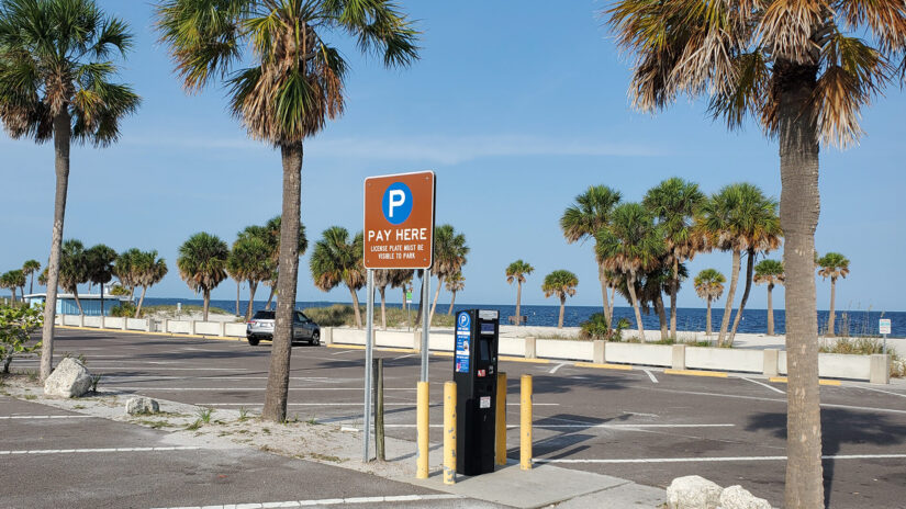 Photo of parking lot at a beach park with a parking pay station between spaces.