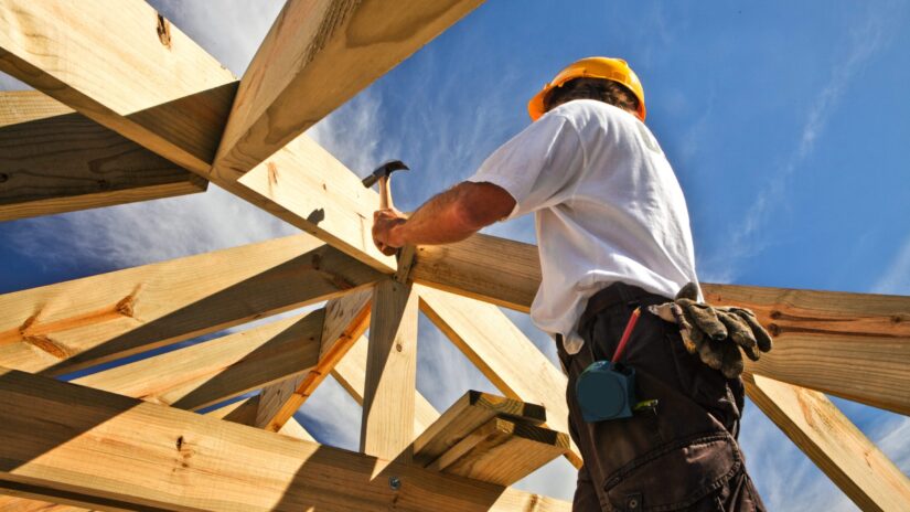 Worker hammers the roof of a house.