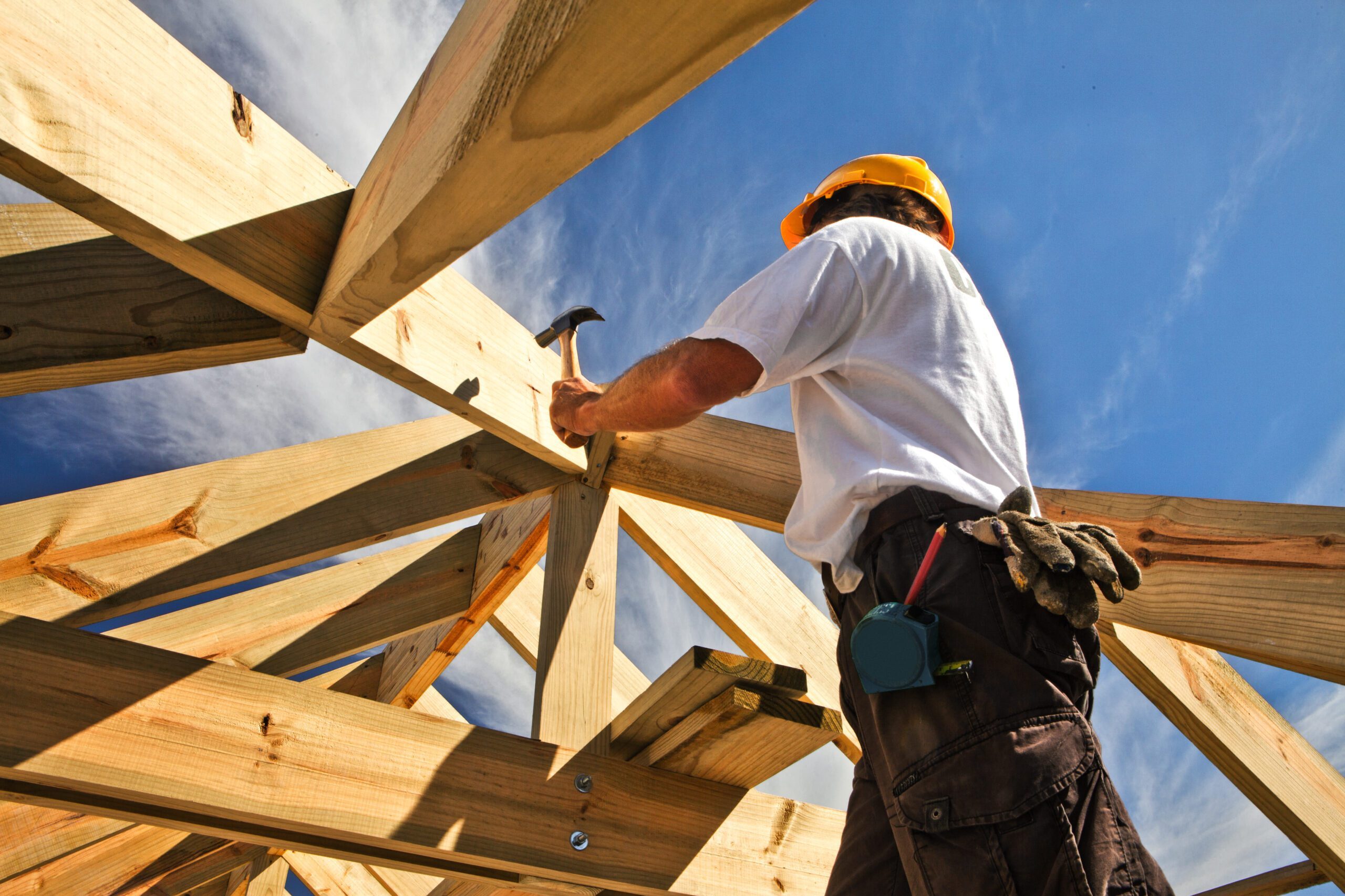 Worker hammers the roof of a house.