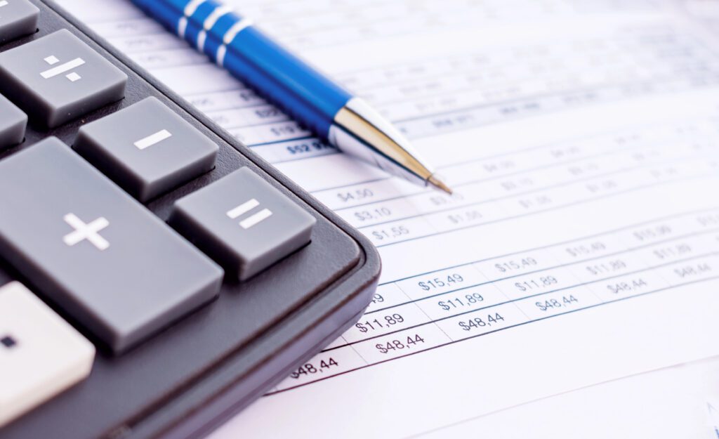 Calculator, pen and financial balance sheet