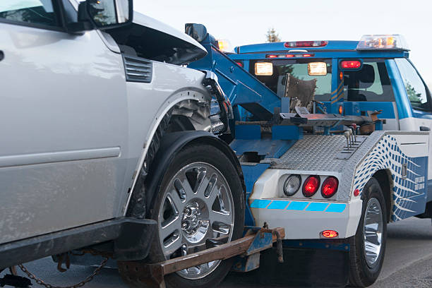 A damaged new vehicle on a tow truck. Medium shot.