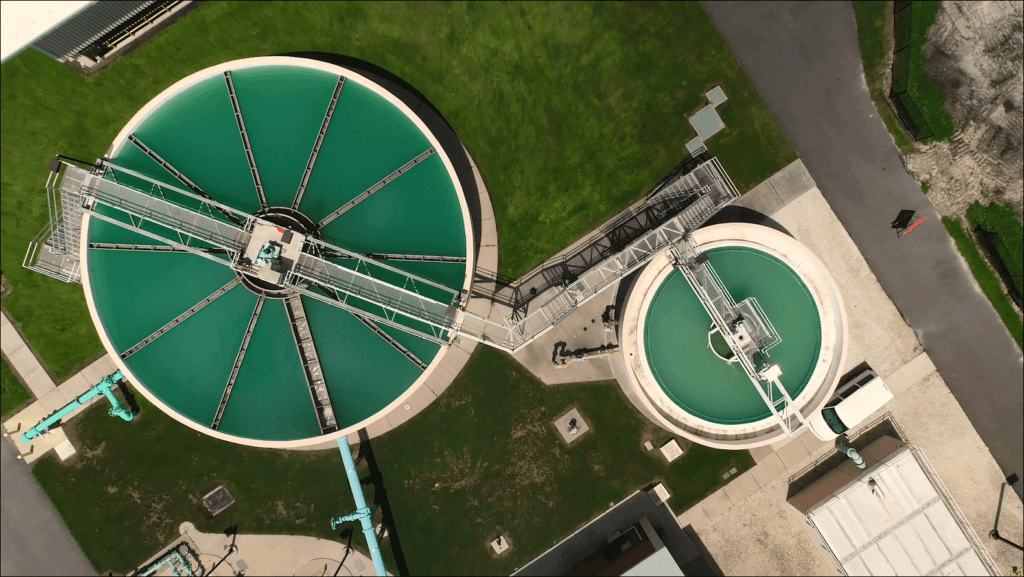 Aerial view of water treatment tanks full of green water.
