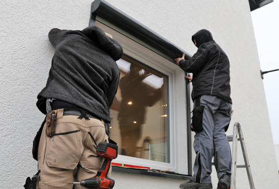 Contractors install a window on a house.