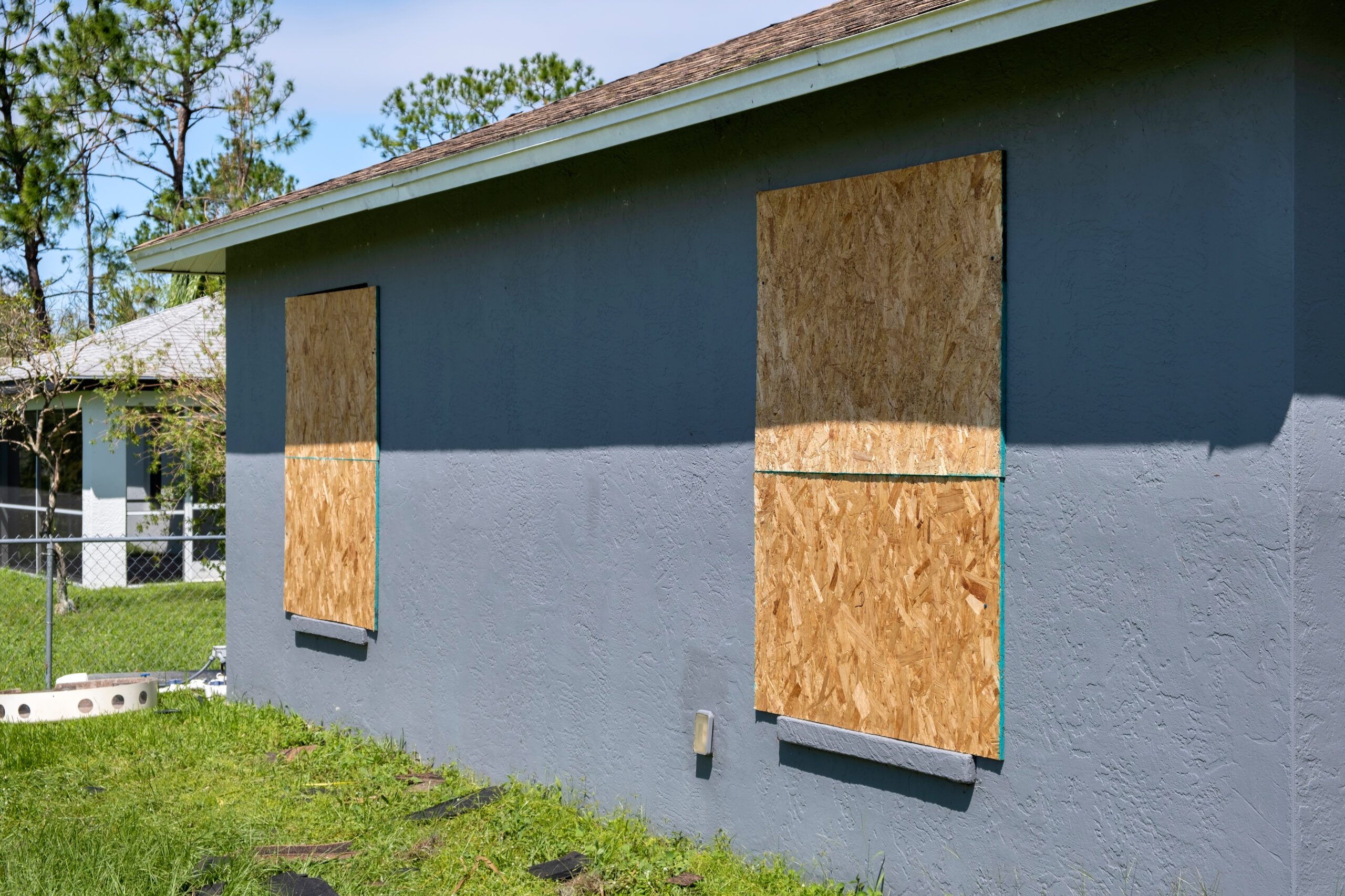 Boarded up windows with plywood storm shutters for hurricane protection of residential house. Protective measures before natural disaster in Florida.