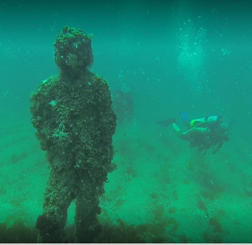 divers underwater with statue