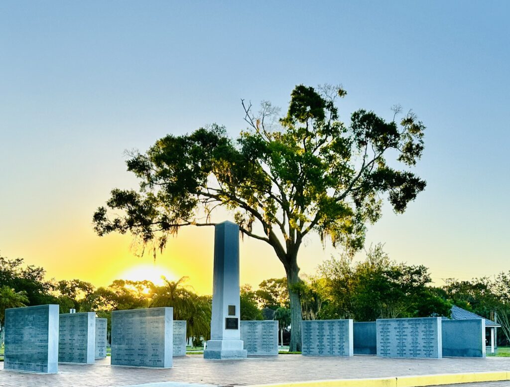 Photo of a war memorial with trees and sun in the background