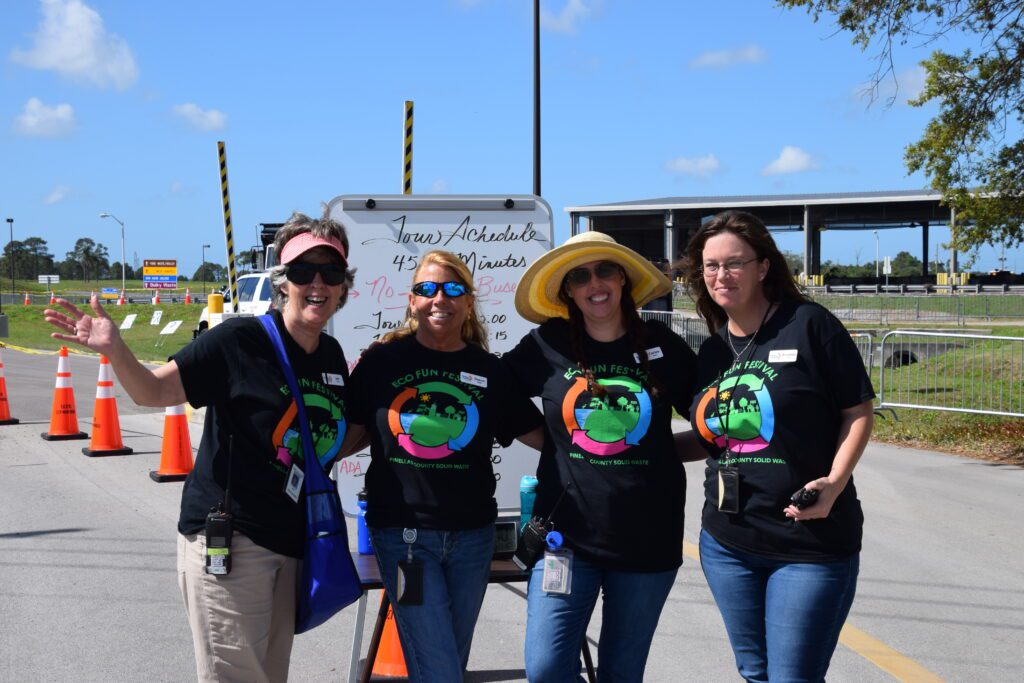 Four people standing with arms around each other outside at an event.