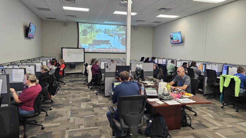 About 19 people sit at in cubicles and at desks taking phone calls in the County Information Center at the Pinellas County Emergency Operations Center