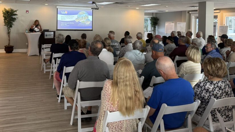A photograph of Commissioner Peters addressing a room full of people seated and watching a presentation.