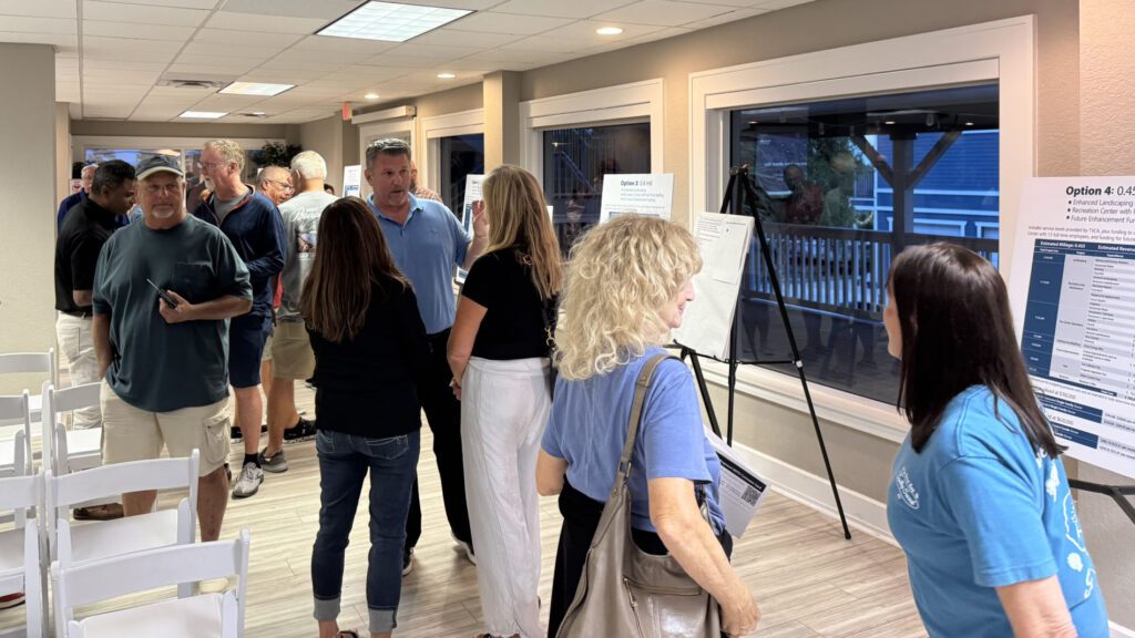 A photograph of community members looking at posters and speaking with staff after the presentation
