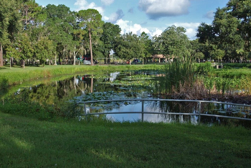 Ridgecrest park in Pinellas County featuring a pond, playground equipment and ball field.