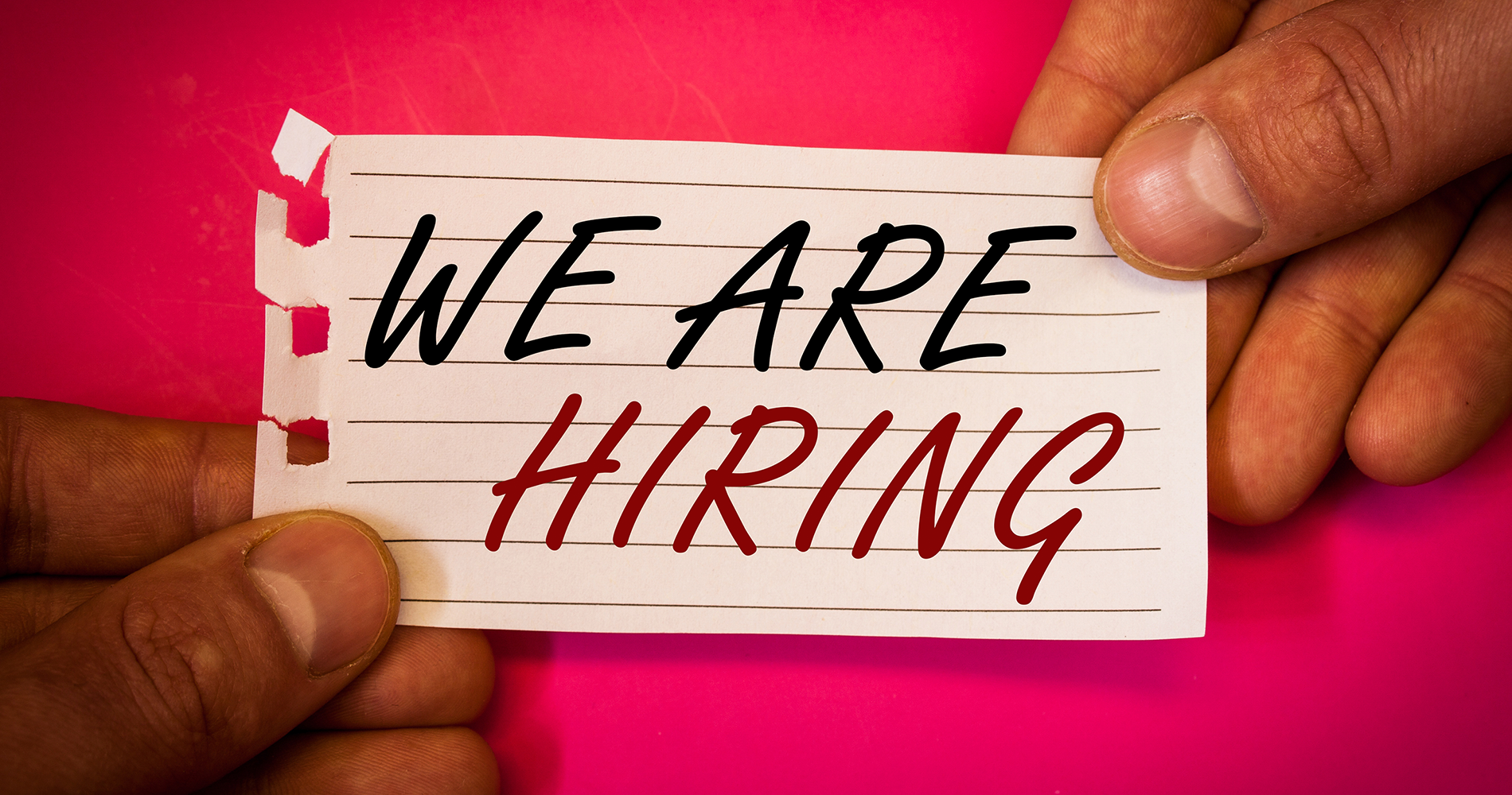 Hands holding sign that says We are Hiring