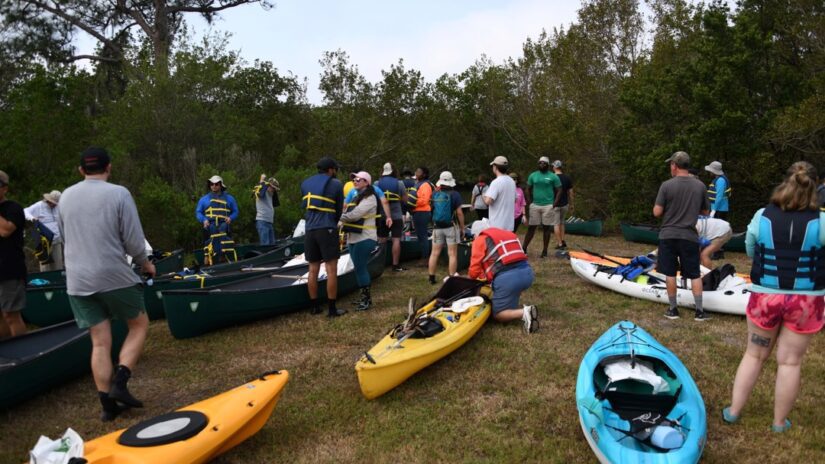 Volunteers standing near a shoreline with canoes