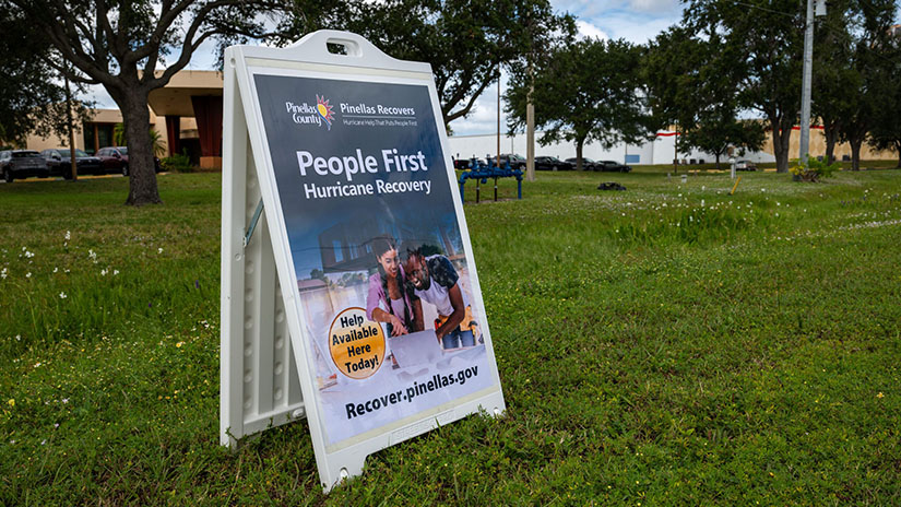 A sandwich board sign announcing that People First Hurricane Recovery help is available onsite today.