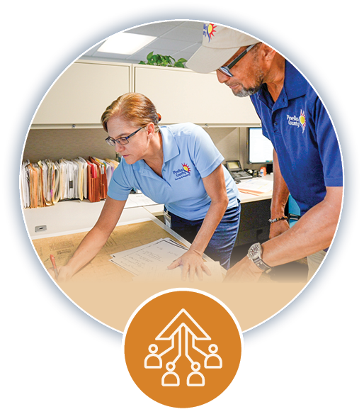 A man and a woman reviewing plans at a table and orange customer service icon