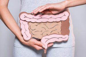 Woman holding paper cutout of a large intestine in front of her stomach