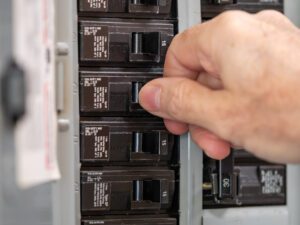 A closeup photo of a hand putting off electrical switches.