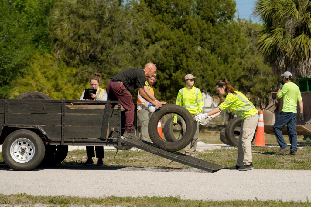 Image of Pinellas County staff rolling a tire out of a trailer. 