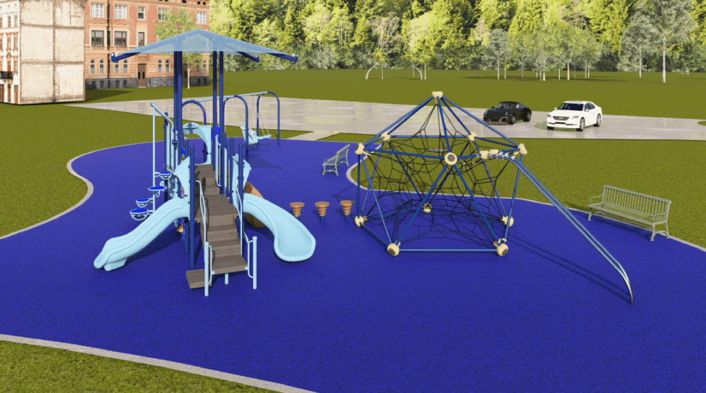 The image shows an outdoor playground built on a bright blue rubberized safety surface with a curved boundary. The playground is set in a wide grassy area surrounded by tall, dense green trees. In the background, multiple multi‑story brick buildings are partially visible behind the treeline. A paved drive‑through area sits behind the playground, with two parked vehicles visible—one light‑colored and one dark‑colored.
The playground features several structures. On the left side, there is a large multi‑level play structure with ramps, guardrails, platforms, and activity panels. The structure includes two light‑blue slides that extend outward from the center—one straight and one gently curved. A shaded roof canopy supported by tall posts covers the central platform. Access to the structure is provided by a staircase with handrails.
To the right of the main structure is a large rope‑climbing dome made of interconnected blue and black ropes attached to a metal frame. The dome sits on the same blue play surface, and it includes elevated climbing points and a curved metal support bar extending downward.
Near the center of the playground are several small, round stepping pods grouped together, and two metal benches—one placed near the climbing dome and the other closer to the play structure.
The sky is bright blue with scattered small clouds, and the lighting suggests a clear, sunny day.