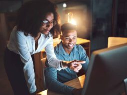 Shot of two businesspeople working together on a computer in an office at night