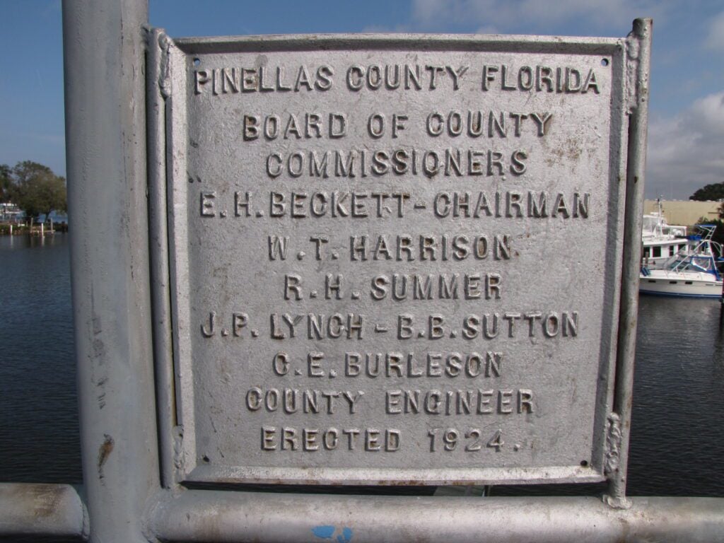 The existing metal plaque signifying the original date of construction, County Commissioners, and engineer of the Beckett Bridge