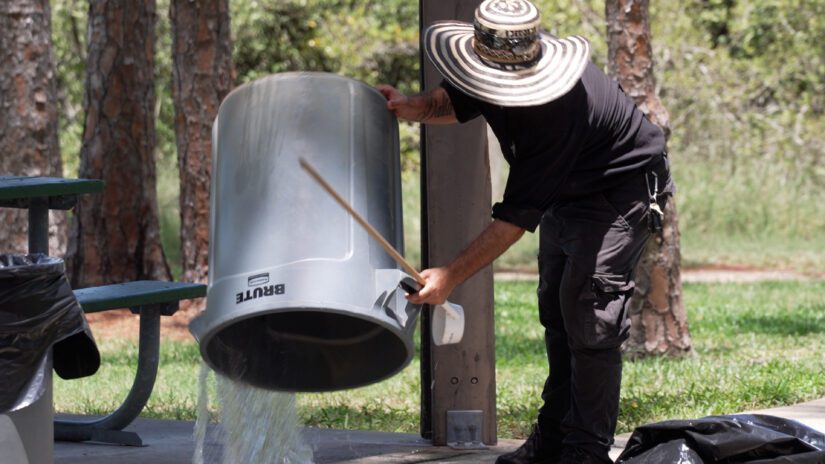 Pinellas County mosquito control staff dumps out standing water from trash can